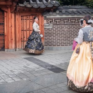 Jeonju, South Korea - August, 05 2017: Young Asian female taking picture of friend in traditional clothes on old town street