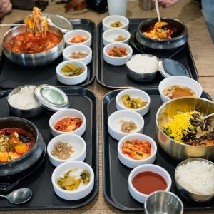Various of korean food with spicy soup, kimchi, noodles and vegetable pickle on tray in restaurant